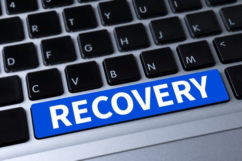 A laptop keyboard with a blue button that says recovery